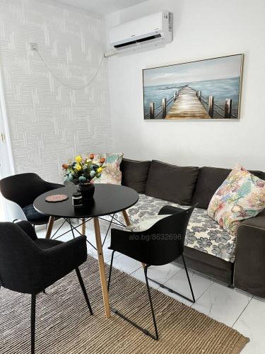 sala de estar con sofá y mesa con sillas en Луксозен двустаен в Балчик с морска гледка en Balchik