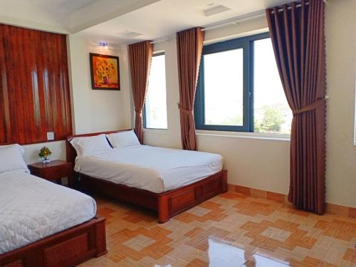 a bedroom with two beds and two windows at GERBERA HOTEL in Quy Nhon