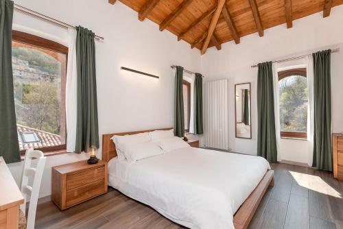 una camera da letto con un grande letto bianco e finestre di Porto di Clanezzo a Clanezzo