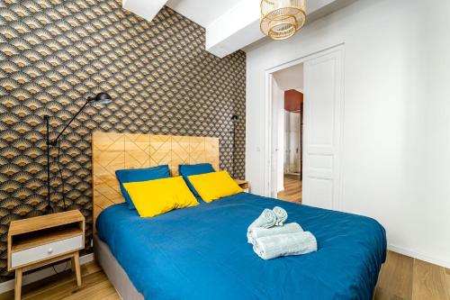 a bedroom with a blue bed with yellow pillows at Plein centre avec "PARKING PRIVE" Voitures électriques bienvenues in Cassis