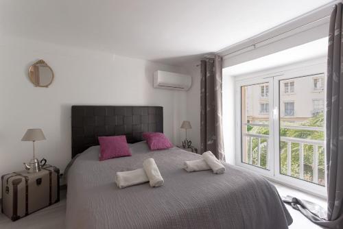 - une chambre avec un grand lit, des oreillers roses et une fenêtre dans l'établissement Duplex Saint-henry by Halldis, à Cannes