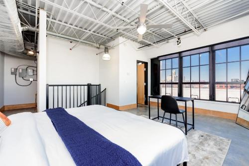 a bedroom with a bed and a desk and windows at CozySuites Spacious 2BR penthouse w Skyline view in Saint Louis