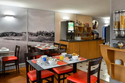 a dining room with two tables and chairs and a kitchen at Logis Hôtel Des Châteaux De La Loire in Tours