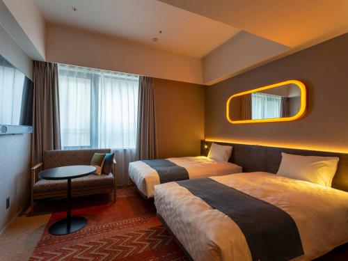 una habitación de hotel con 2 camas y una silla en Royal Park Hotel Kurashiki, en Kurashiki