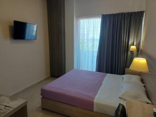 a bedroom with a bed and a window with a television at The Santo George Beach Resort in Amoudara Herakliou