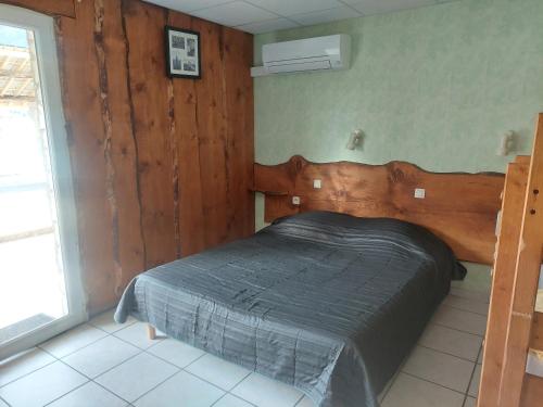 a bedroom with a bed with a wooden headboard at Hotel Restaurant Lancheton in Saint-Julien-Mont-denis