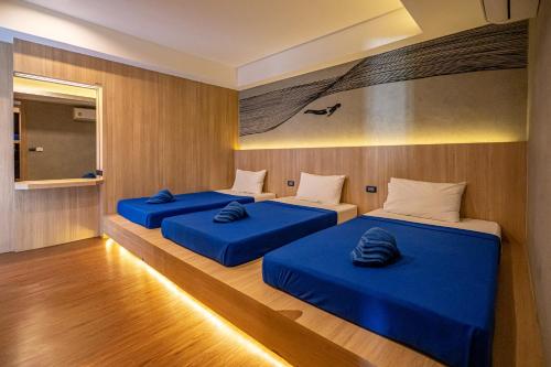 three beds in a room with blue sheets at Patong Poshtel in Patong Beach