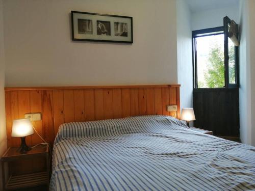 a bedroom with a bed with two lamps and a window at Planta baja tranquila Besiberri 11 in Pla de l'Ermita