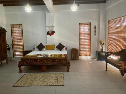 a bedroom with a bed and two windows and a couch at Lutwala Bungalows and Private Villa in Gili Trawangan