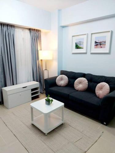 a living room with a black couch and a table at Fully-Airconditioned 2-BR Unit near BGC in Manila