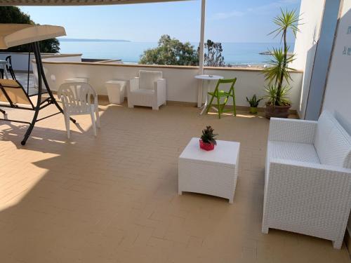 a patio with white furniture and a table and chairs at La Bussola in Porto Palo