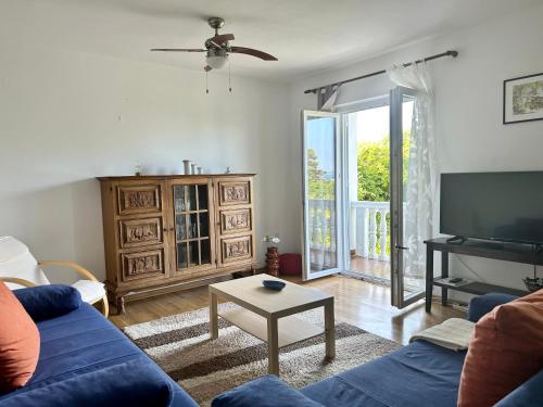 a living room with a blue couch and a television at Villa Roseal in Povljana
