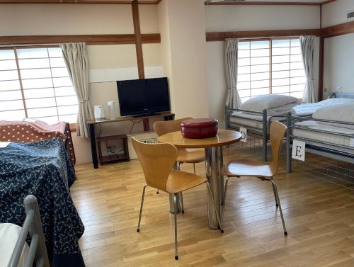 a room with a table and chairs and a bedroom at Kawaguchiko Station Inn in Fujikawaguchiko