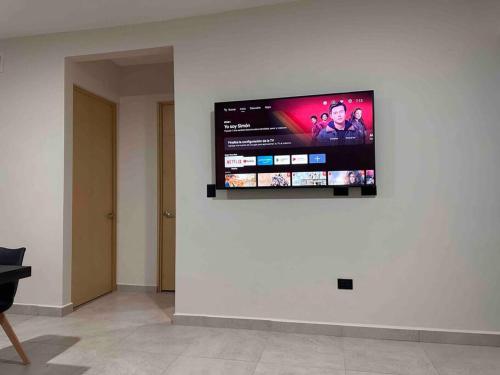 TV de pantalla plana colgada en una pared blanca en Departamento de lujo nuevo con Alberca y Gimnasio, en Ciudad Obregón
