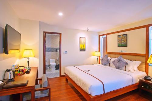 a bedroom with a bed and a desk with a computer at Poulo Wai Hotel & Apartment in Phnom Penh