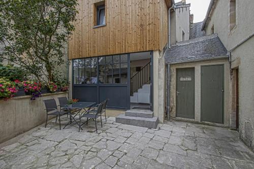 a patio with a table and chairs in front of a building at La cour des teinturiers in Bayeux