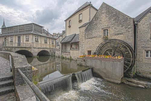 a canal in a city with a bridge and buildings at La cour des teinturiers in Bayeux