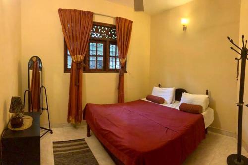 a bedroom with a red bed and a window at Dili's Home Stay in Kandy