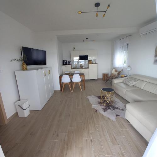 a living room with a white couch and a kitchen at Apartmani Tin in Starigrad-Paklenica