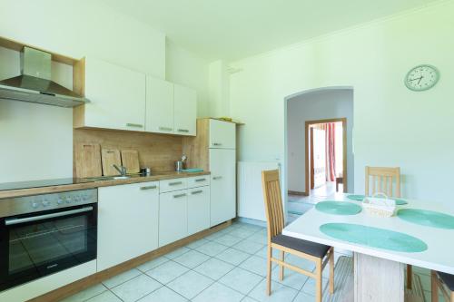 uma cozinha com armários brancos e uma mesa com cadeiras em Appartment Gailtalblick em Nötsch