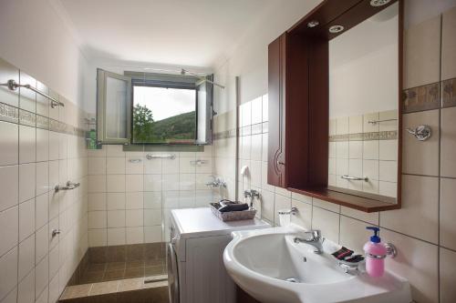 uma casa de banho com um lavatório e um espelho em Garbis Garden View em Valsamáta