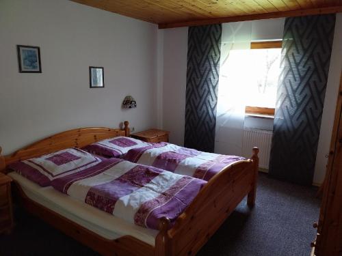 a bedroom with a wooden bed and a window at Ferienwohnungen im Himmelreich in Lam