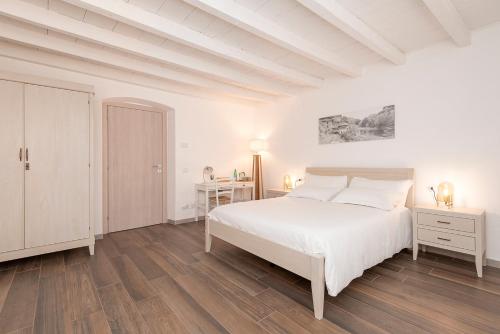a white bedroom with a bed and a desk at Porto di Clanezzo in Clanezzo