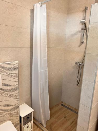 a shower with a white shower curtain in a bathroom at Apartmani Tin in Starigrad-Paklenica