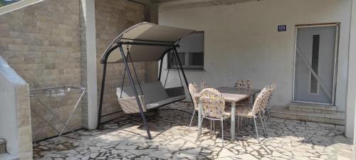 a patio with a table and chairs and a grill at Apartmani Maslina Žuljana in Žuljana