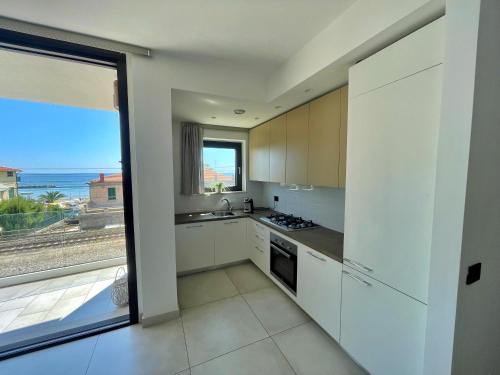 a kitchen with white cabinets and a view of the ocean at Mimì a Mare in Grottammare