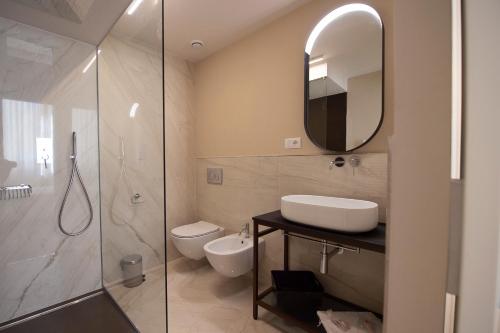 a bathroom with a sink and a toilet and a mirror at Villino Micol camere a due passi dal mare in Marina di Carrara