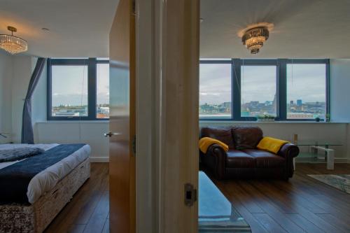 a bedroom with a bed and a couch and windows at Bright & Comfortable 2-Bedroom Central Flat with Parking in Liverpool