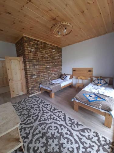a room with two beds and a brick wall at Guest House Jekshen in Imeni Karla Marksa
