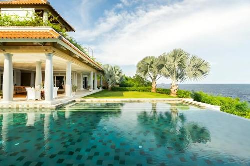 a house with a swimming pool next to the ocean at Raaga Samudra Villa in Padangbai