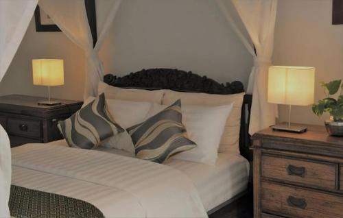 a bedroom with a bed with two night stands and two lamps at Raaga Samudra Villa in Padangbai
