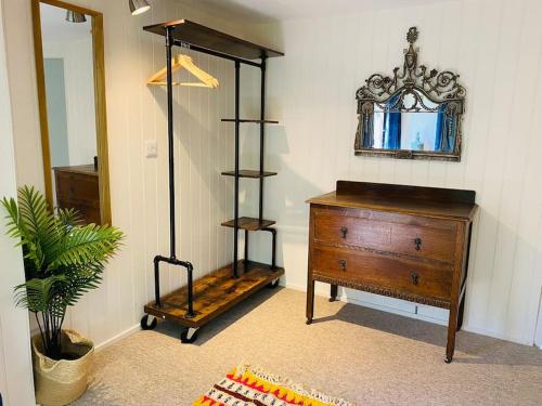 a room with a dresser and a mirror and a wooden dresser at Olive's Cabin in Helston