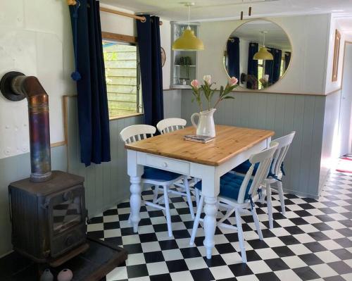 a dining room with a table with chairs and a stove at Olive's Cabin in Helston