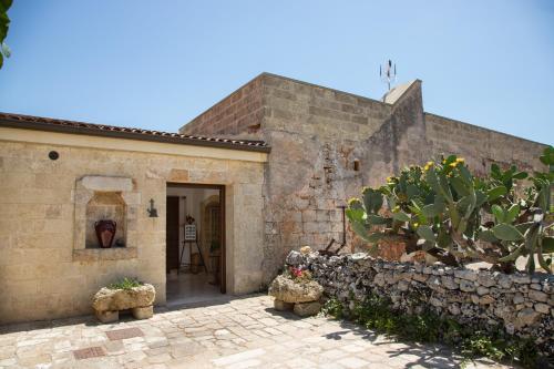 una vecchia casa in pietra con una porta e un cactus di Antica Masseria Ficazzana - Tenuta a Marina di Pescoluse