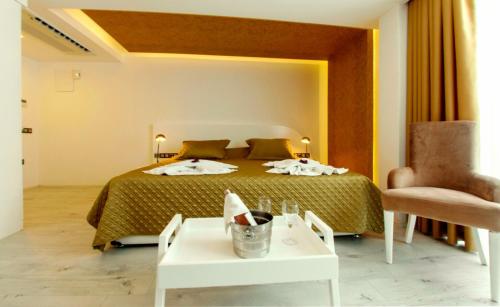 a bedroom with a bed and a chair and a table at Rhapsody Hotel & Spa Kalkan in Kalkan