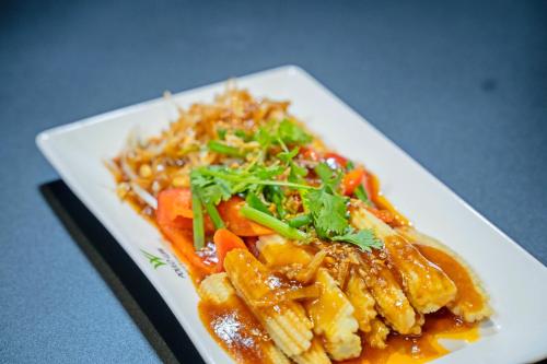 a plate of food with pasta and vegetables on a table at Poulo Wai Hotel & Apartment in Phnom Penh