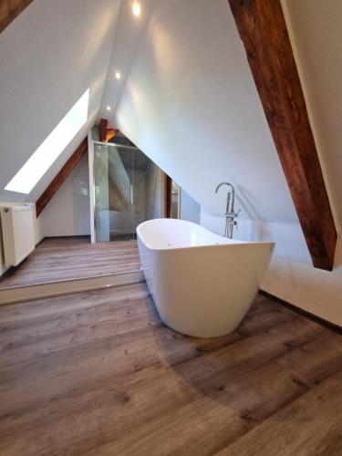 baño con bañera blanca en el suelo de madera en 5 Sterne Bahnhoftraum, Appartement "Waldliebe", en Braunfels