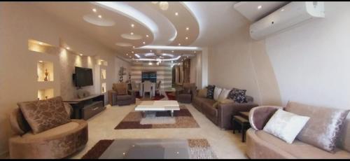 uma grande sala de estar com sofás e uma televisão em شقة فيو نيلي no Cairo