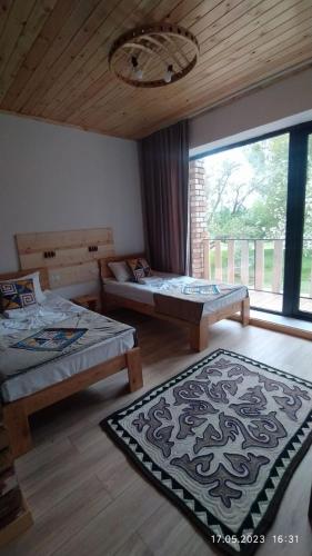 a room with two beds and a large window at Guest House Jekshen in Imeni Karla Marksa