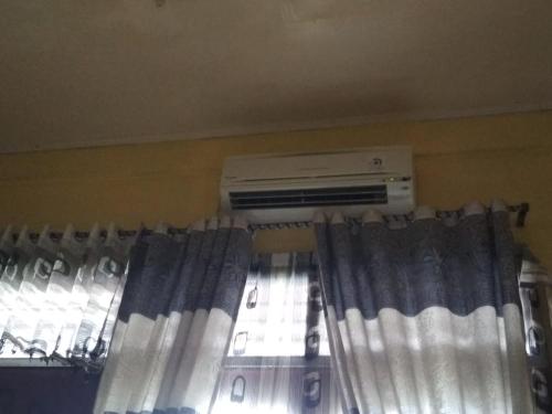 1 dormitorio con aire acondicionado y ventana en Home Sweet Dewi en Kualasimpang