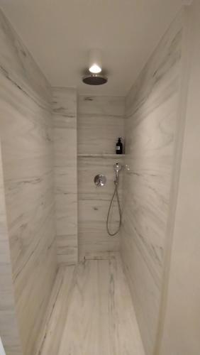 uma casa de banho com chuveiro e paredes em mármore branco em Chania Locals Flat em Chania