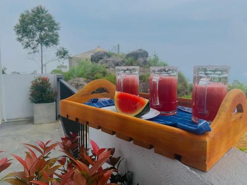 a tray with two glasses of juice and a slice of watermelon at The Fog House in Haputale