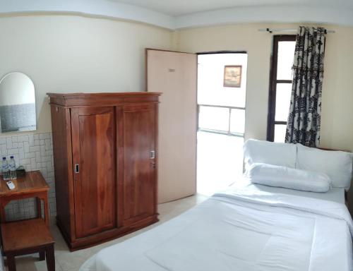 a bedroom with a bed and a wooden cabinet at Pesona Room and restaurant in Labuan Bajo