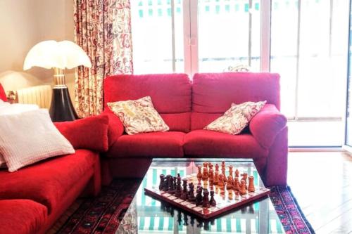 a living room with a red couch and a chessboard on a table at Apartamento Miramar in Hondarribia