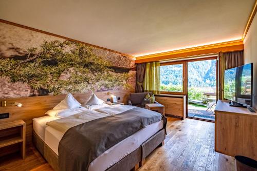 a bedroom with a large bed and a television at Hotel Grien in Ortisei