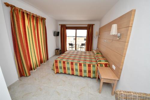 1 dormitorio con cama, mesa y ventana en Hotel Vista Sol, en Cala Ratjada